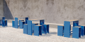 Tabouret de Bar d'Extérieur Indre By en métal bleu et bois, placé dans un espace extérieur avec sol gravillonné.