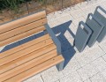 Fahrradständer und Holzbank auf gepflastertem Platz.