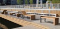 Öffentliche Sitzbank Vesterbro 4-Sitzer mit Rückenlehne aus Eiche auf Holzterrasse.