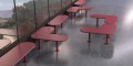 Banc Public Sans Dossier Sydhavn en forme de L, installé devant une grande fenêtre, avec assises rouges modernes et design minimaliste.