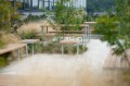 Banc Public Sans Dossier Holmen 3 Places en bois et métal dans un jardin paysager moderne.