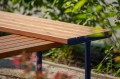 Banc public sans dossier Holmen en bois en forme de L dans un jardin.