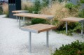 Tabouret d'extérieur Holmen en bois et métal, placé dans un jardin sur gravier.