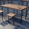 Table d'extérieur Holmen 150 cm 4-6 places en bois sur terrasse pavée avec verre et tasse.