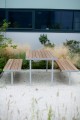 Table d'extérieur Holmen 150 cm avec bancs en bois sur pieds métalliques dans un jardin.