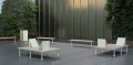 Poubelle de rue Holmen sur une terrasse moderne, entourée de bancs et de verdure.