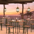Ensemble de Bar Holmen avec table et quatre tabourets sur une terrasse au coucher du soleil.