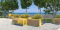 Banc public sans dossier 4 places Christiania en bois et métal jaune dans un parc en bord de mer.