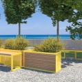 Jardinière d'extérieur Christiania en bois et métal jaune dans un jardin avec vue sur la mer.