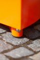 Close-up of Valby Public Backless Bench | Quarter Round bright orange leg on pavement.