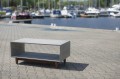 Concrete sideboard with wooden legs on a pavement near a marina.