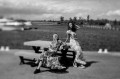 Two women in long dresses relaxing on a picnic bench by the water.
