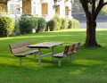Banc et table en acier galvanisé dans un jardin verdoyant.