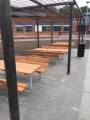 Banc et table en bois avec structure en acier galvanisé sous une pergola.