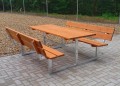 Banc et table en acier galvanisé avec assises en bois sur une terrasse pavée.