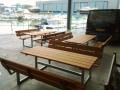 Bänke und Tische aus verzinktem Stahl auf einer Terrasse neben einem Hafen.