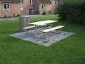 Table et banc en acier galvanisé dans un espace extérieur vert.