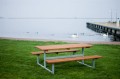 Bench &amp; table (galvanized steel) in front of a lakeside promenade.