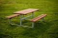 Table de pique-nique en métal galvanisé avec bancs intégrés sur pelouse verte.