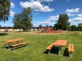 Banc et table en acier galvanisé sur une pelouse avec une aire de jeux en arrière-plan.