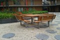 Mobilier d'extérieur en bois et métal avec bancs et table, installé dans une cour moderne.