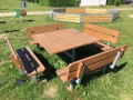 Holztisch mit quadratischen Bänken im Freien.