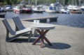 Coffee table w/ concrete table top near modern chairs by a marina.