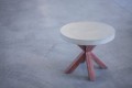 Round coffee table with concrete top and wooden legs.
