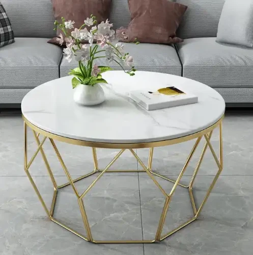Table basse en métal doré avec plateau rond en MDF blanc, décorée d'un vase à fleurs.