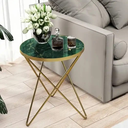 Table basse ronde moderne avec plateau en marbre vert et cadre en métal doré, décorée de fleurs blanches et de bouteilles de parfum.