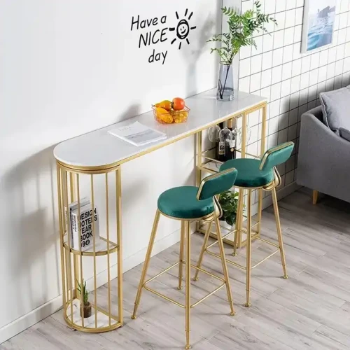 Table et chaises élégantes en métal doré et velours vert dans un intérieur moderne.