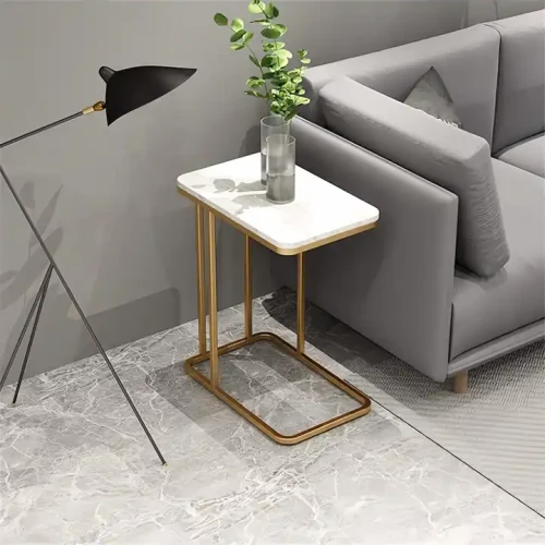 Modern Golden Metal Side Table next to a grey sofa in a living room with a vase on top.