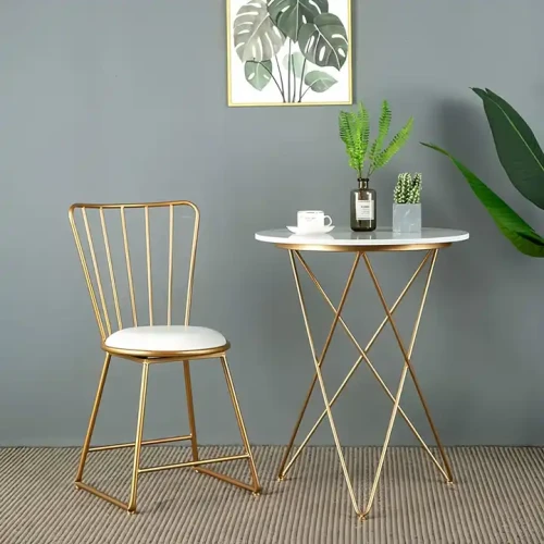 Chaise moderne en métal doré avec assise blanche devant une petite table assortie, idéale pour la salle à manger.
