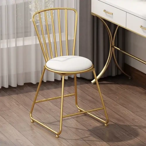 Modern gold metal dining chair with white seat cushion.
