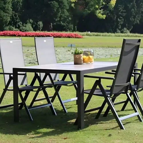 Outdoor patio set with foldable metal chairs and table on grass.