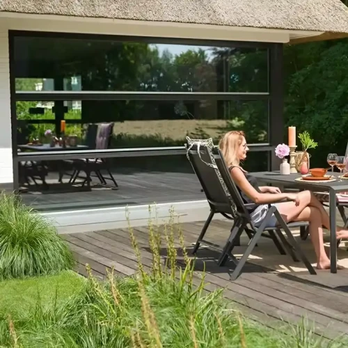 Frau sitzt auf Modernes Design Klappbarer Tragbarer Metallrahmen Outdoor-Möbel Für Camping Garten Metallstuhl, Terrasse im Garten.