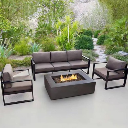 Mobilier de salon extérieur avec structure métallique et coussins autour d'un foyer, situé sur une terrasse de jardin.