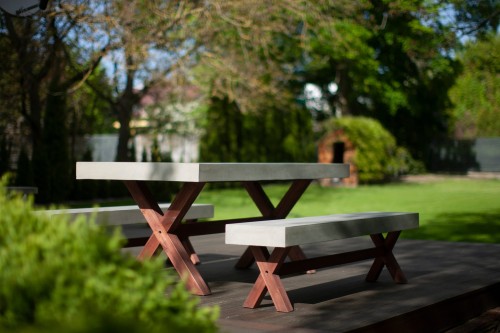 Garden set consisting of a concrete table and benches with wooden legs in a garden.