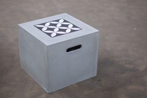 Concrete cube with decorative white and black patterned top.