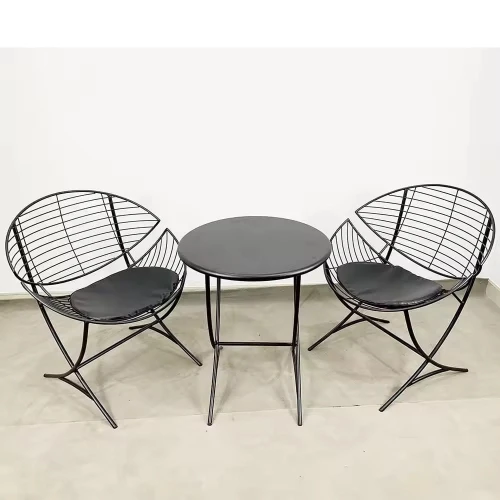 Deux chaises de meubles style nordique avec coussins noirs, accompagnées d'une table ronde assortie.
