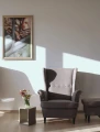 Concrete table next to a gray armchair and flowers in a vase.