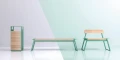 Nørrebro Street Litter Bin next to matching bench and chair in a modern, minimalistic design with green structure and wooden panels.