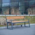 Amager 4-personers offentlig bænk med ryglæn og armlæn foran moderne bygning.
