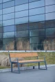 Amager 4 Seater Public Backrest Bench w/ Armrest placed outdoors in front of a modern glass building.