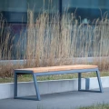 Amager 4 Seater Public Backless Bench placed outdoors near tall grass.