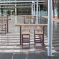 Amager Outdoor Bar Stool w/ Footrest and matching outdoor table set on a modern tiled patio.
