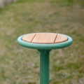 Nordhavn Outdoor Stool | 45 cm with green frame and wooden seat in a garden setting
