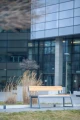 Offentlig bænk Amager med ryglæn og armlæn foran kontorbygning.