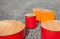 Valby Outdoor Stool | 48 cm - Red and orange outdoor stools with wooden tops on cobblestone pavement.
