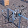 Sølv cykel parkeret i Nyboder Cykelstativ på brostensbelagt plads.